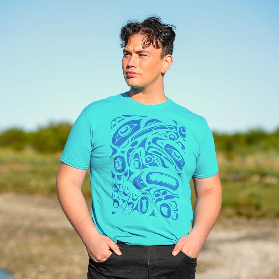 Model wearing unisex t-shirt raven and eagle motif by indigenous artist in blue