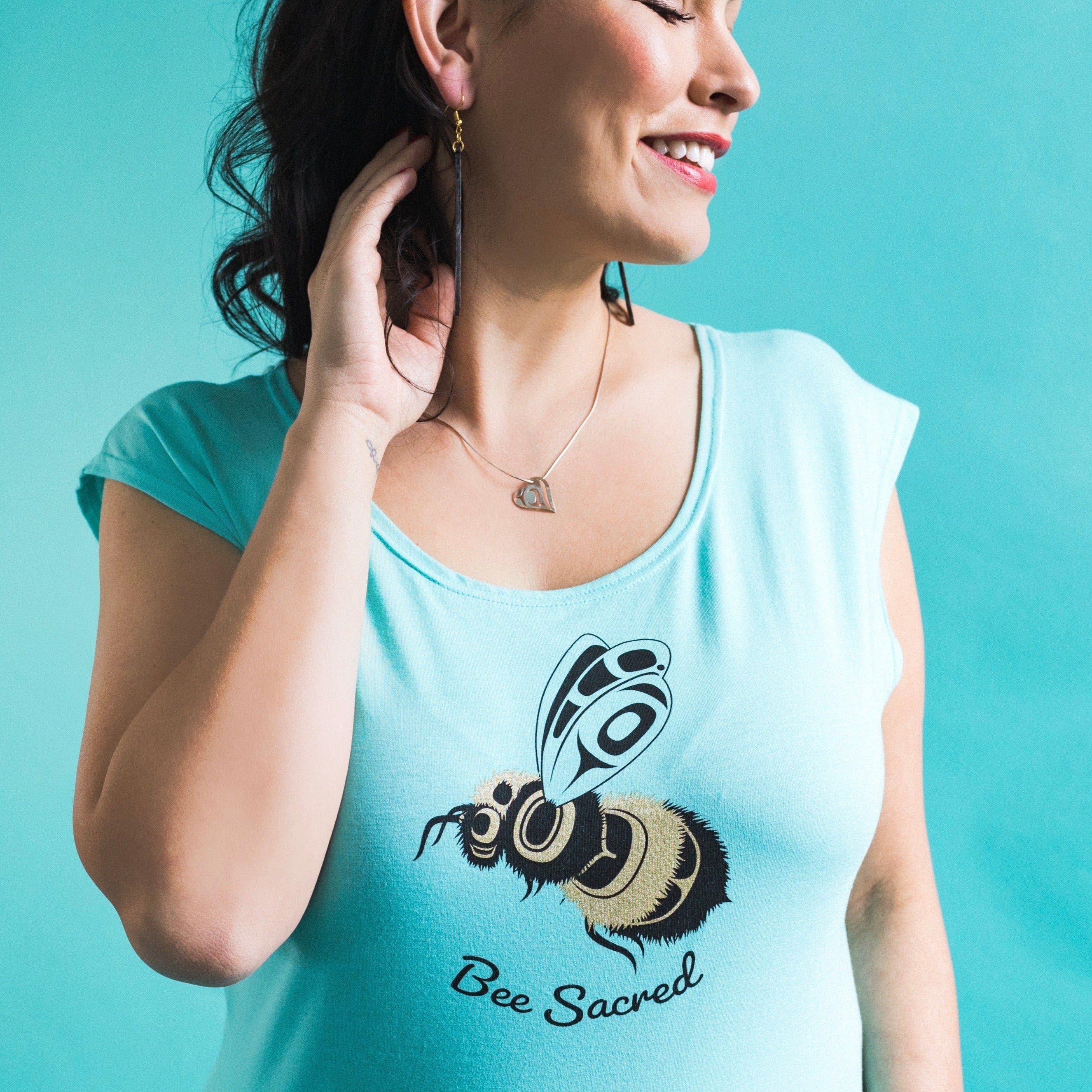 Model wearing Women's Bee Sacred cap sleeve top by indigenous artist Andy Everson