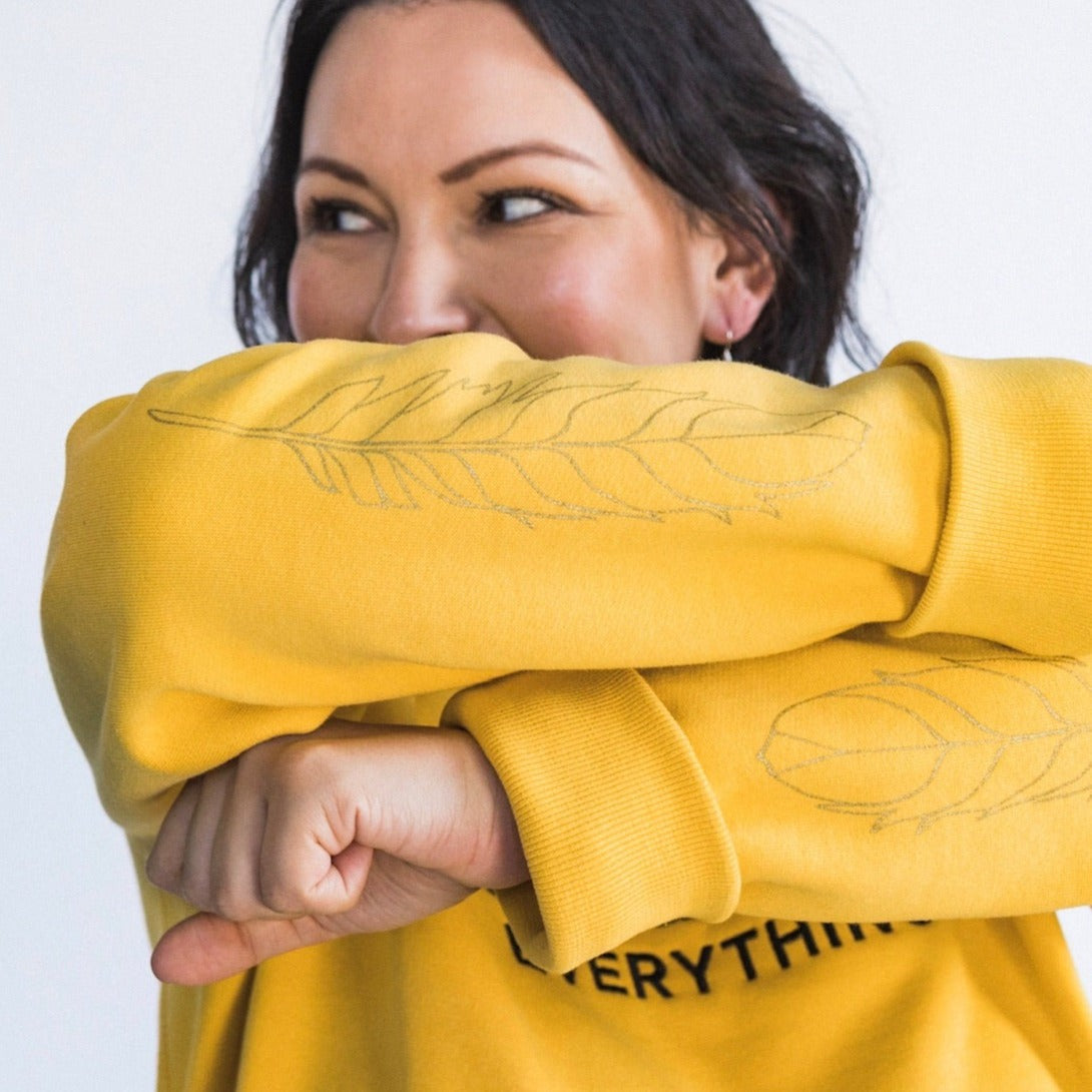 Closeup model wearing Indigenize everything sweatshirt in yellow by indigenous artist