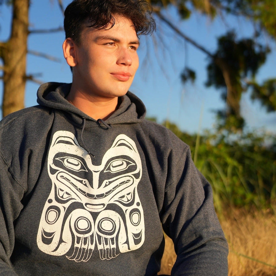 Model outside unisex hoodie featuring a bear by indigenous artist