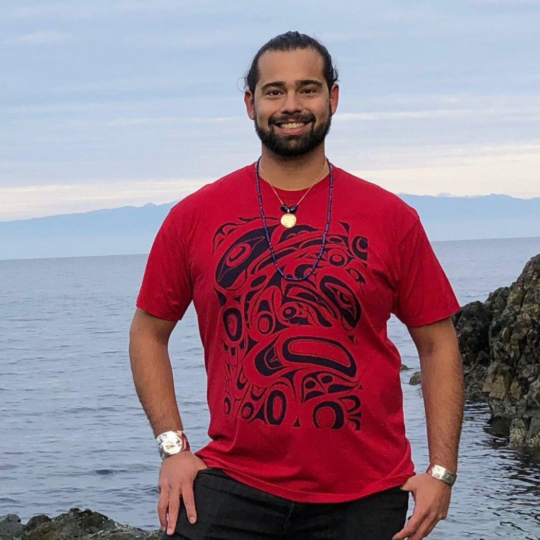Model wearing unisex t-shirt raven and eagle motif by indigenous artist in red