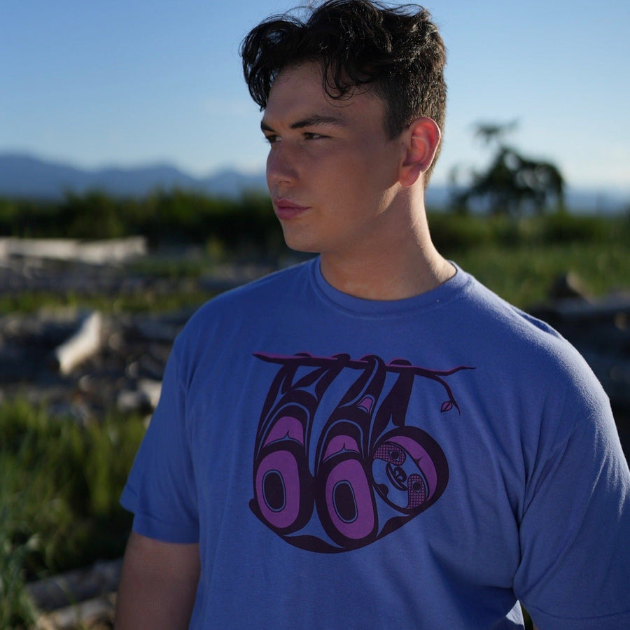 Model outside wearing unisex t-shirt featuring a sloth by indigenous artist