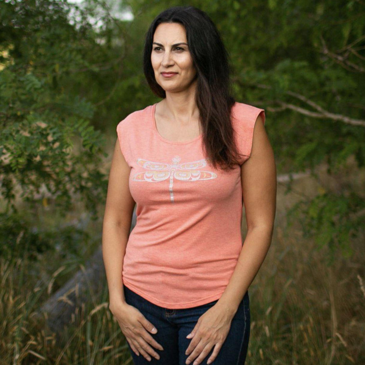 Model outside wearing womens top created by indigenous artist featuring a dragonfly