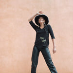Model wearing womens organic cotton top by indigenous artist featuring hummingbirds wearing a hat