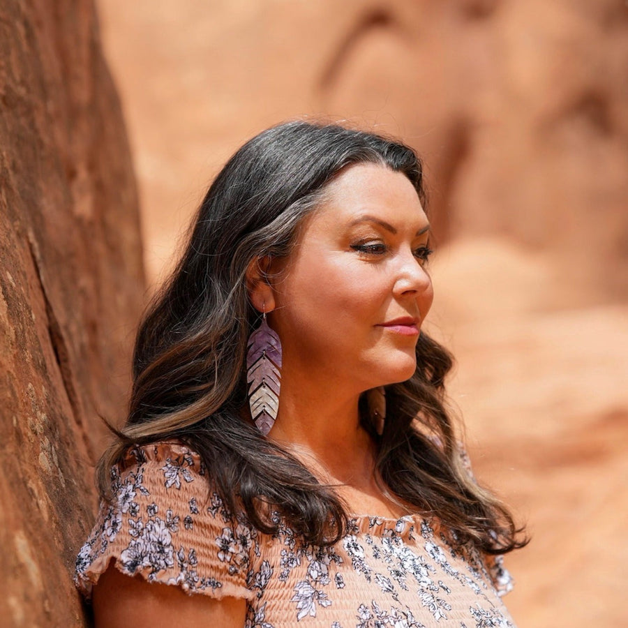 Model wearing tiered feather earrings by indigenous artist acrylic